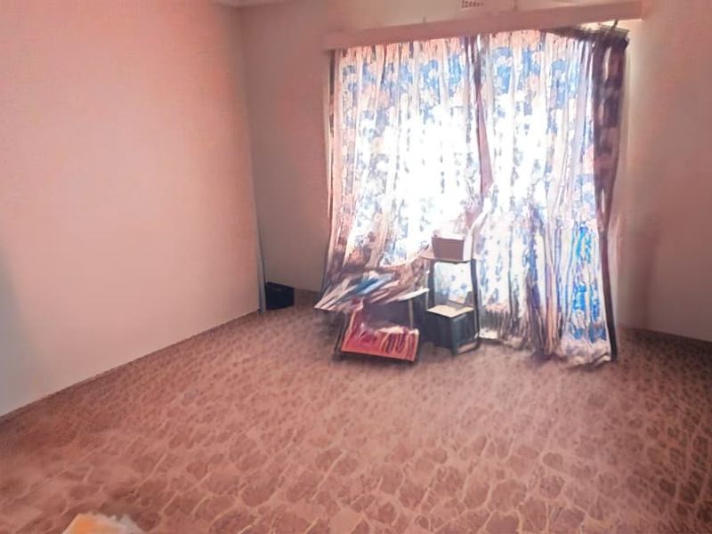 A vacant bedroom featuring patterned flooring and a window with a curtain rail, offering a blank canvas for renovation and interior design updates.