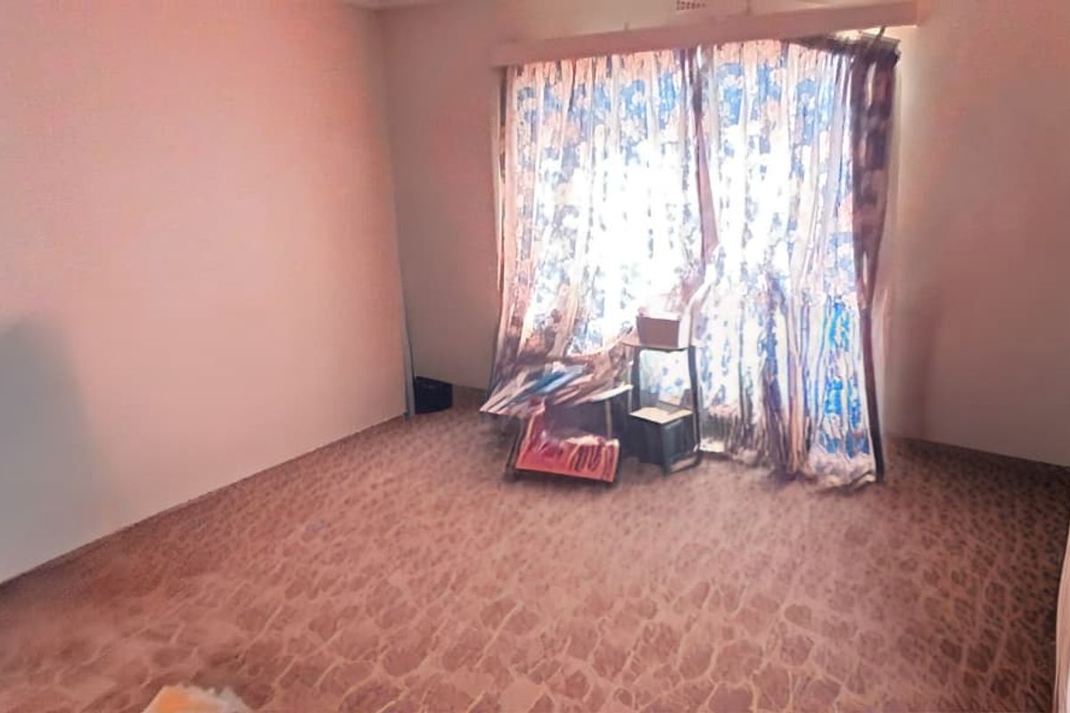 A vacant bedroom featuring patterned flooring and a window with a curtain rail, offering a blank canvas for renovation and interior design updates.