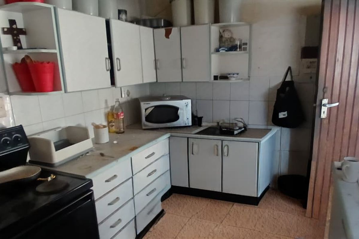 A dated kitchen featuring white cabinetry, tiled backsplash, and tiled flooring, offering significant potential for modernization and renovation.