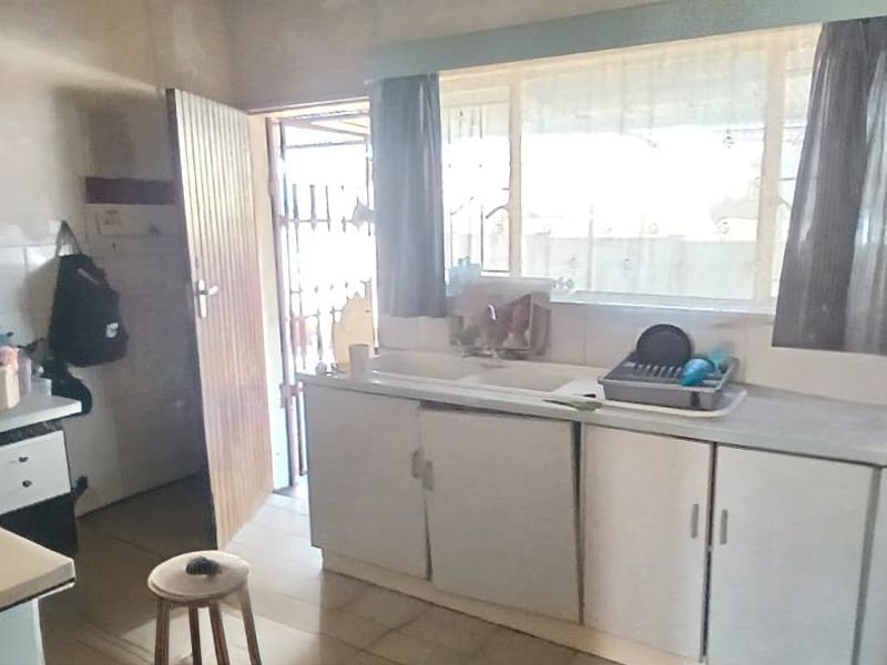 A functional kitchen featuring built-in cabinetry, a double sink, and tiled finishes, offering potential for modernization and layout optimization.