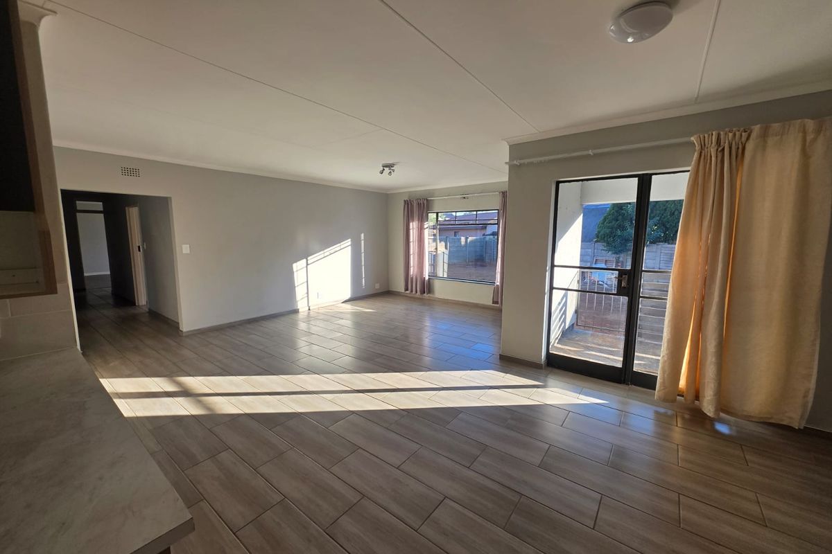 Spacious open-plan living area featuring modern tiled flooring, ample natural light, and direct access to an outdoor patio through a sliding glass door.