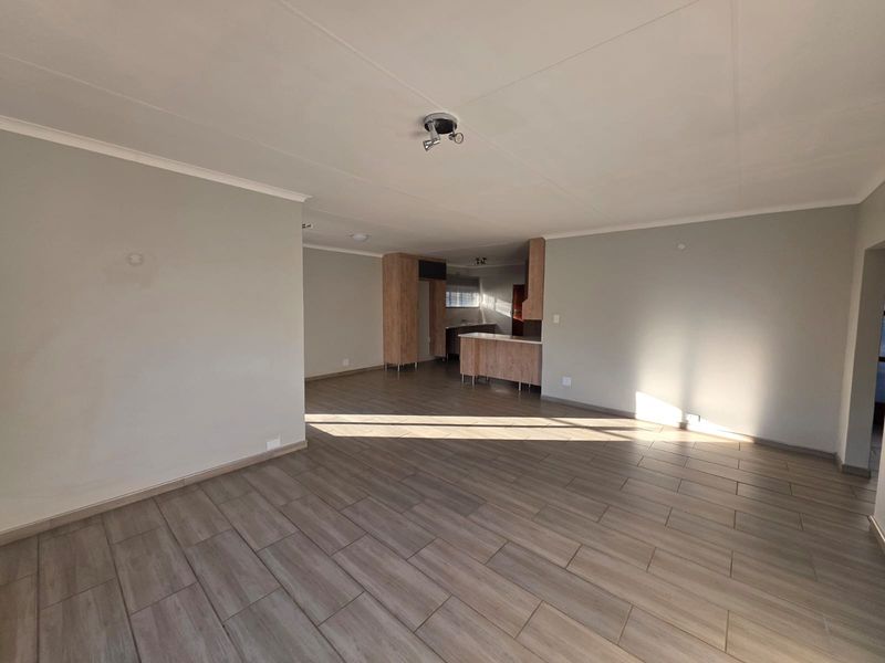Spacious open-plan living area featuring modern tiled flooring and a functional kitchen with built-in cabinetry and a central island.
