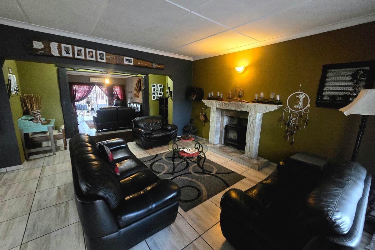 Spacious living room featuring a prominent fireplace with a wood-burning stove, tiled flooring, and an open-plan layout connecting to an adjacent living area.
