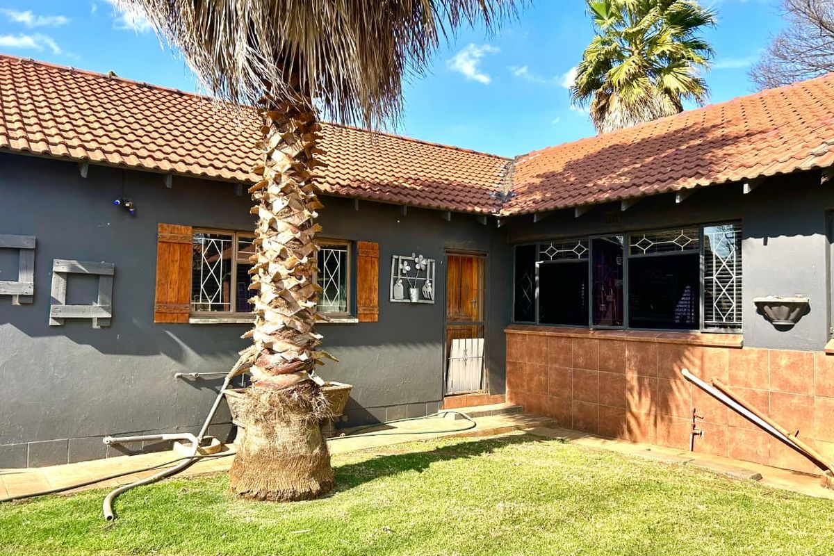 Rear exterior view of the house featuring terracotta roof tiles, leaded glass windows with wooden shutters, and a small garden area.