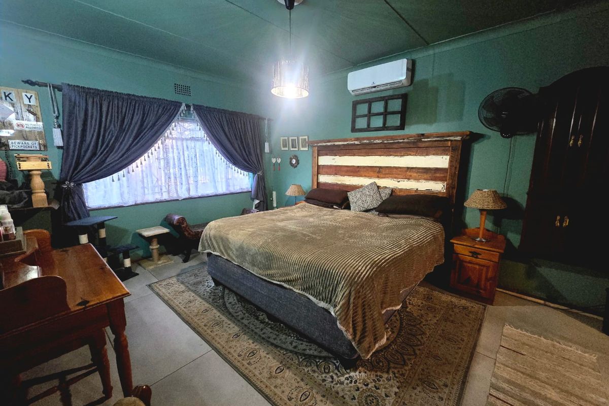 A spacious bedroom featuring tiled flooring, a wall-mounted air conditioning unit, and a ceiling pendant light, offering a comfortable and functional living space.