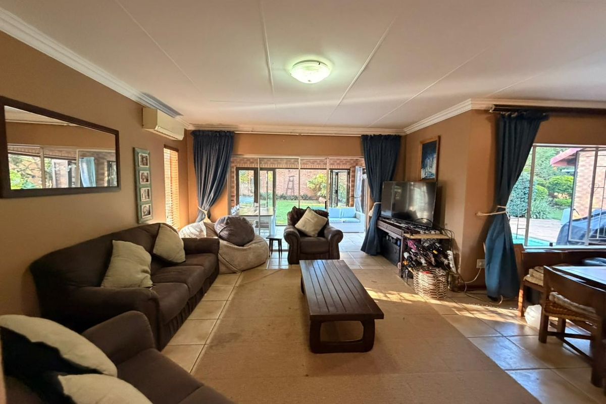 Spacious living room featuring tiled flooring, split-system air conditioning, and large sliding glass doors providing direct access to the outdoor patio and garden area.