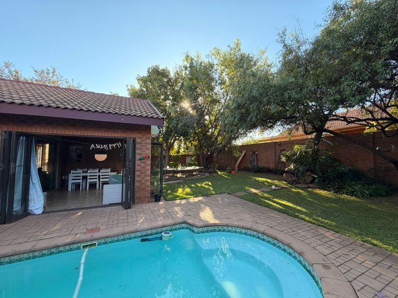 Outdoor pool area featuring brick paving, a swimming pool, and direct access to the home through bi-fold doors, set within a landscaped garden.