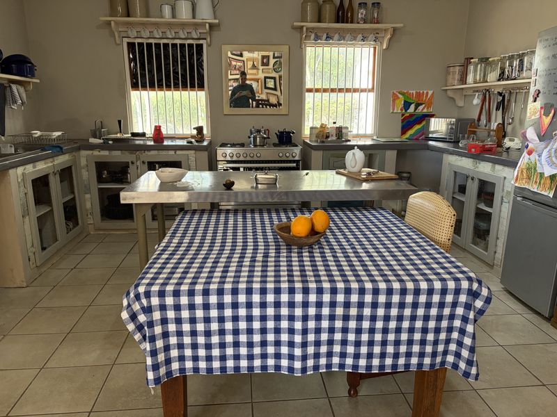 A rustic farmhouse kitchen featuring a central stainless steel island, freestanding stove, and ample built-in cabinetry with tiled flooring.