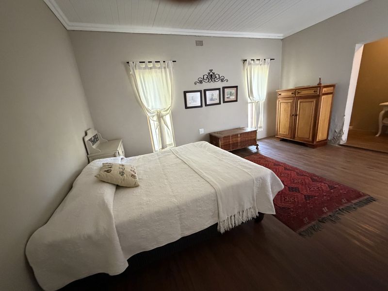 Spacious bedroom featuring timber flooring, tongue and groove ceiling, and neutral wall tones, offering a comfortable and classic living space.