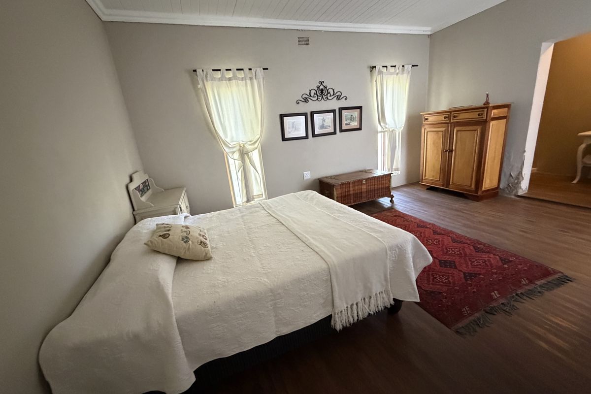 Spacious bedroom featuring timber flooring, tongue and groove ceiling, and neutral wall tones, offering a comfortable and classic living space.