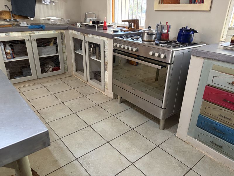 A rustic kitchen featuring a stainless steel gas stove, built-in cabinetry with wire mesh inserts, and tiled flooring.