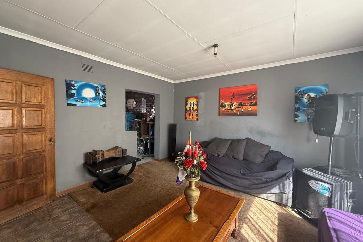 A living room featuring grey walls, a combination of tiled and carpeted flooring, and a timber door leading to an adjacent space.