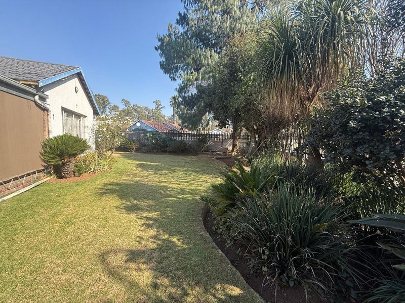 A well-maintained rear garden featuring a manicured lawn, established trees, and mature shrubbery, providing a private outdoor space.