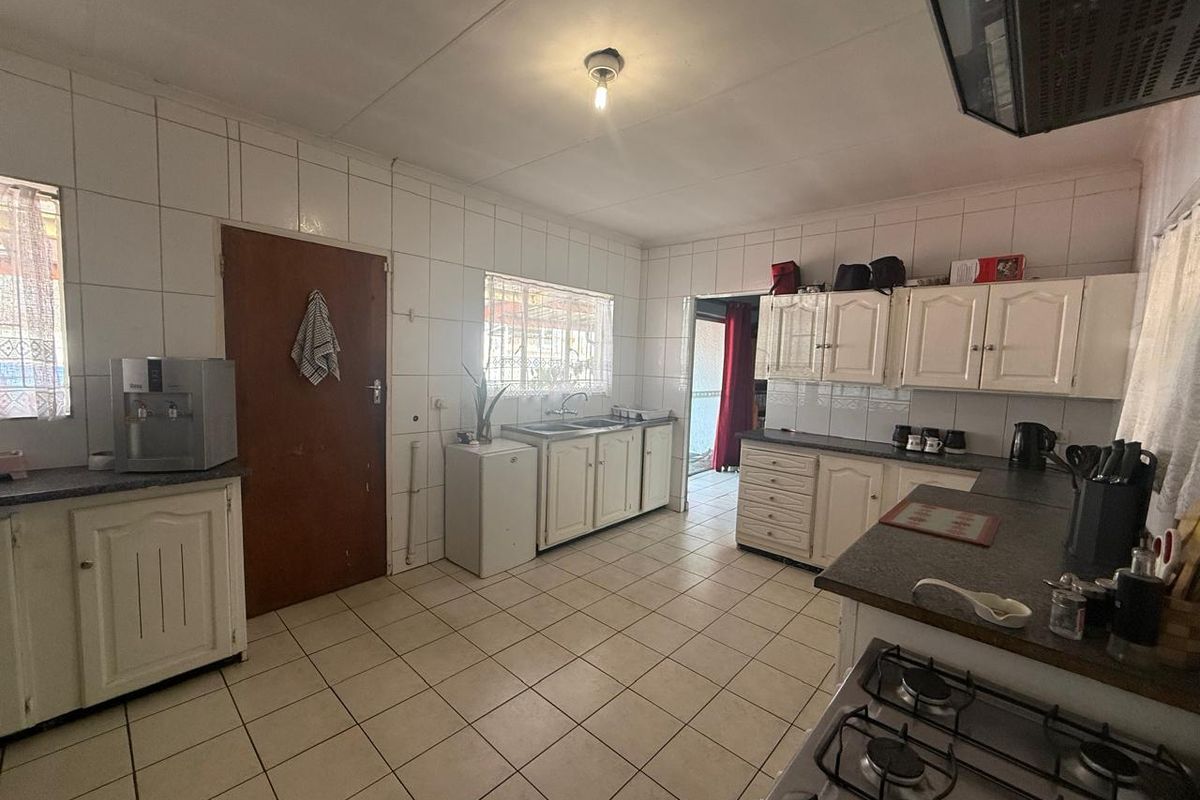 A functional kitchen featuring tiled walls and flooring, built-in cabinetry, laminate countertops, and a gas hob with an extractor fan.