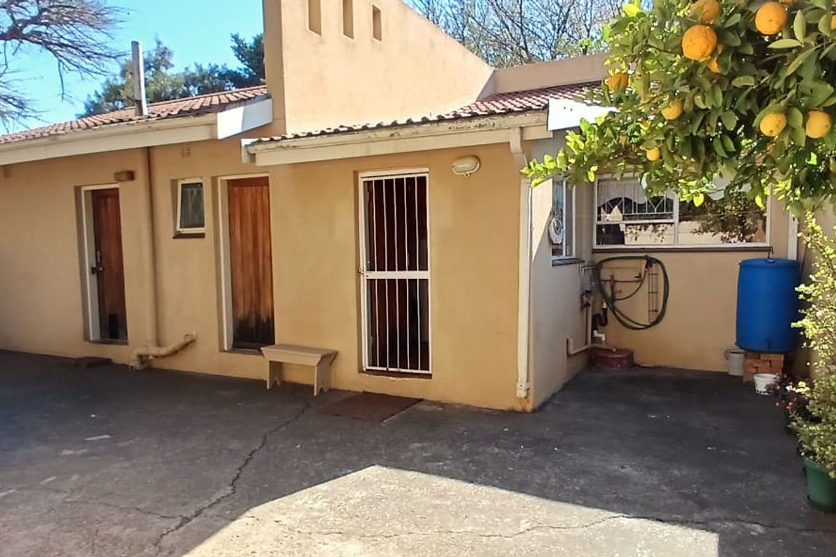 Rear exterior view of the property featuring a paved courtyard area, security gates, and tiled roof structure.