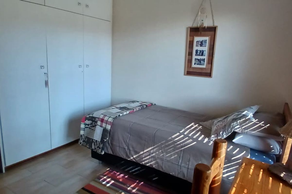 A functional bedroom featuring built-in cupboards and laminate flooring, offering a clean and practical living space.
