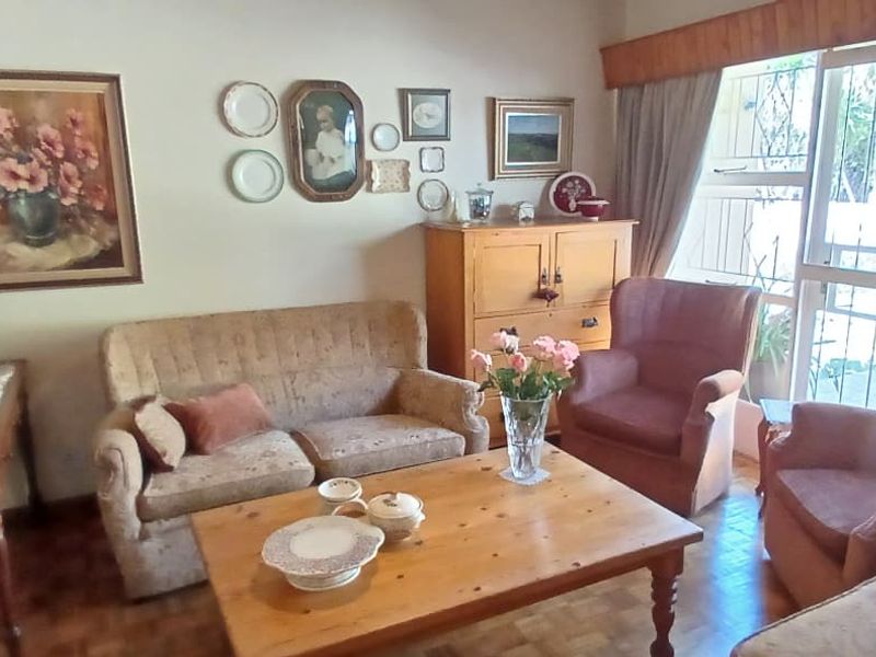 A cozy living room featuring parquet flooring and a sliding glass door with security gate, providing access to the outdoor area.
