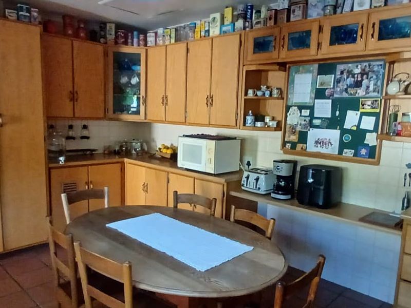 A traditional kitchen featuring extensive wooden cabinetry, tiled backsplash, and tiled flooring, offering a functional layout with ample storage space.