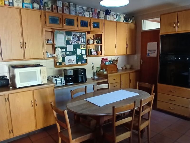 A functional kitchen featuring extensive wooden cabinetry, a built-in oven, extractor fan, tiled backsplash, and a double sink with tiled flooring.