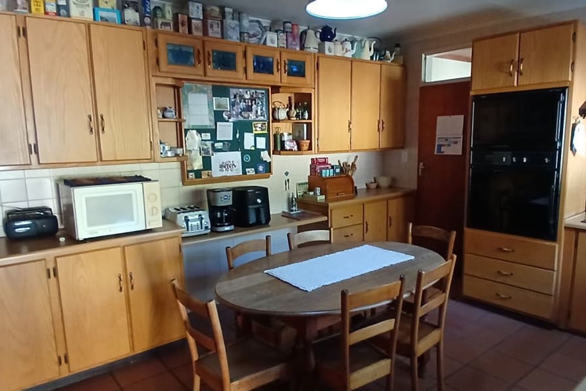 A functional kitchen featuring extensive wooden cabinetry, a built-in oven, extractor fan, tiled backsplash, and a double sink with tiled flooring.