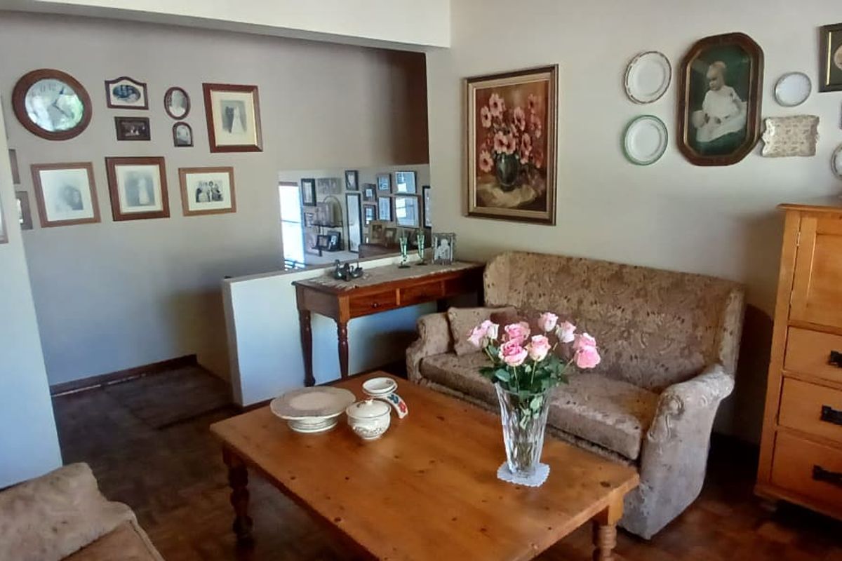 A living room area featuring parquet flooring and a half-height partition wall, providing a view into the adjacent hallway space.