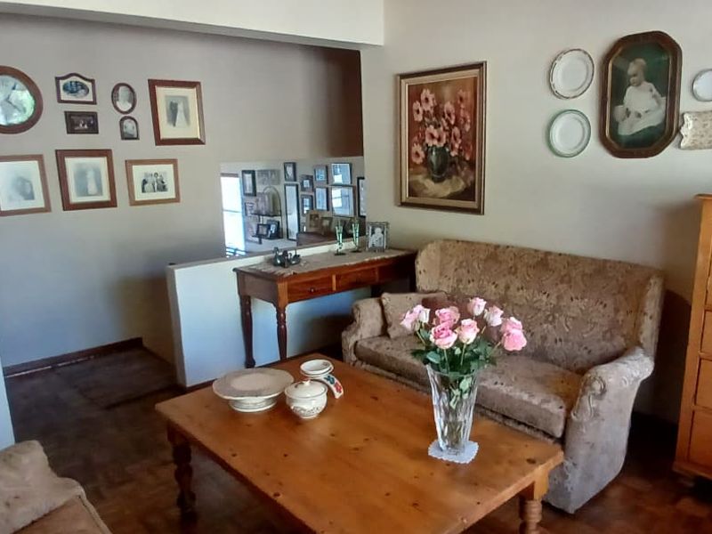 A living room area featuring parquet flooring and a half-height partition wall, providing a view into the adjacent hallway space.