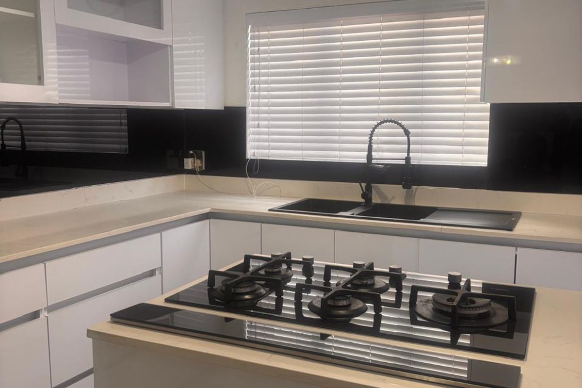 Modern kitchen featuring white cabinetry, stone countertops, a black glass splashback, and a built-in gas cooktop with a contemporary gooseneck faucet.