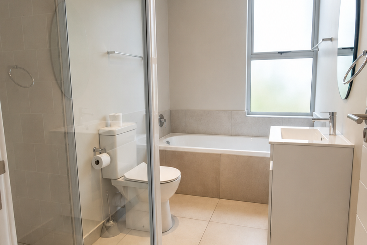 Modern bathroom featuring a glass-enclosed shower, built-in bathtub, vanity with basin, and neutral floor-to-ceiling tiling.