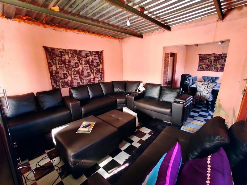 Living room area featuring checkered floor tiles and an exposed corrugated metal ceiling, requiring cosmetic updates to improve the overall finish.