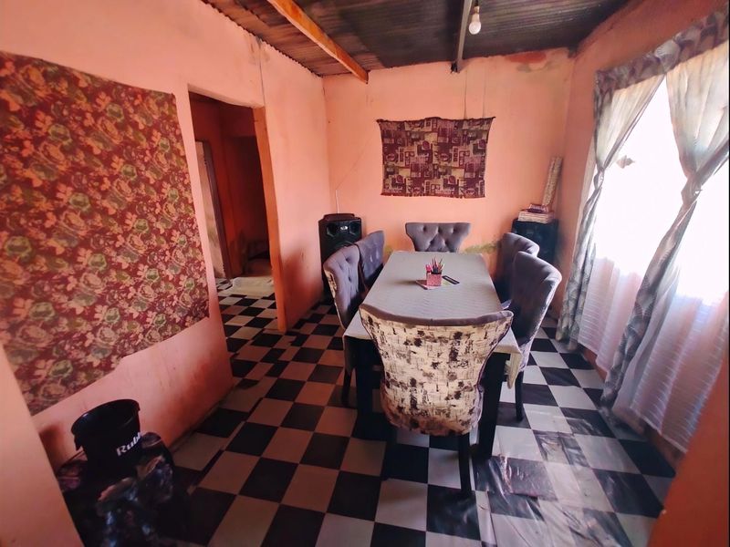 A dining room featuring a checkered tile floor and exposed corrugated metal ceiling, requiring cosmetic updates to improve the overall finish and aesthetic.