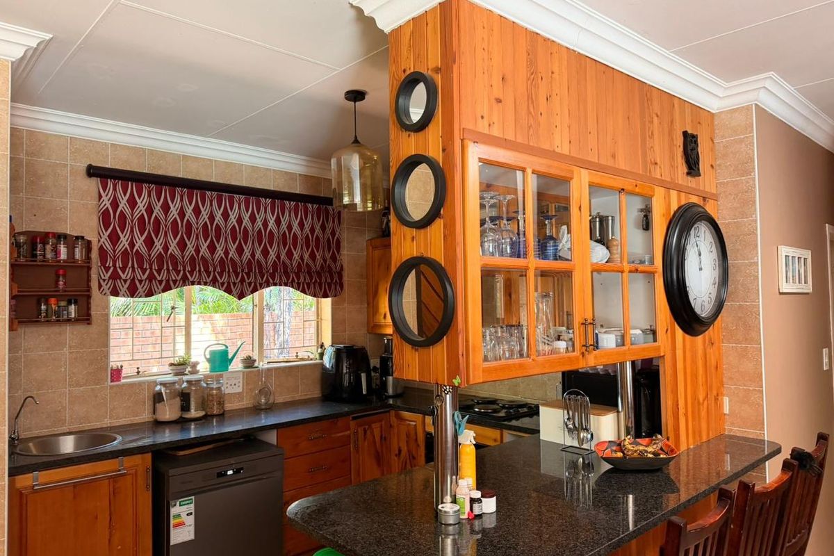 A functional kitchen featuring granite countertops, wooden cabinetry, and a breakfast bar, with a tiled backsplash and classic crown molding details.