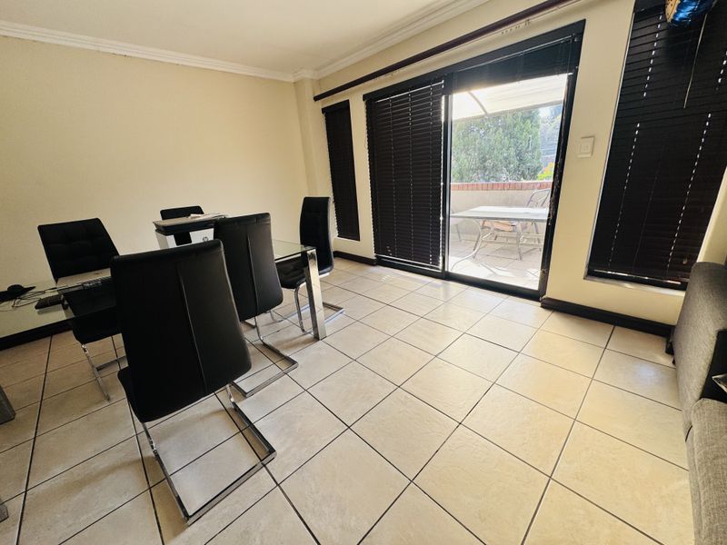 A dining area featuring tiled flooring, coved ceilings, and a large sliding glass door providing access to an outdoor patio space.