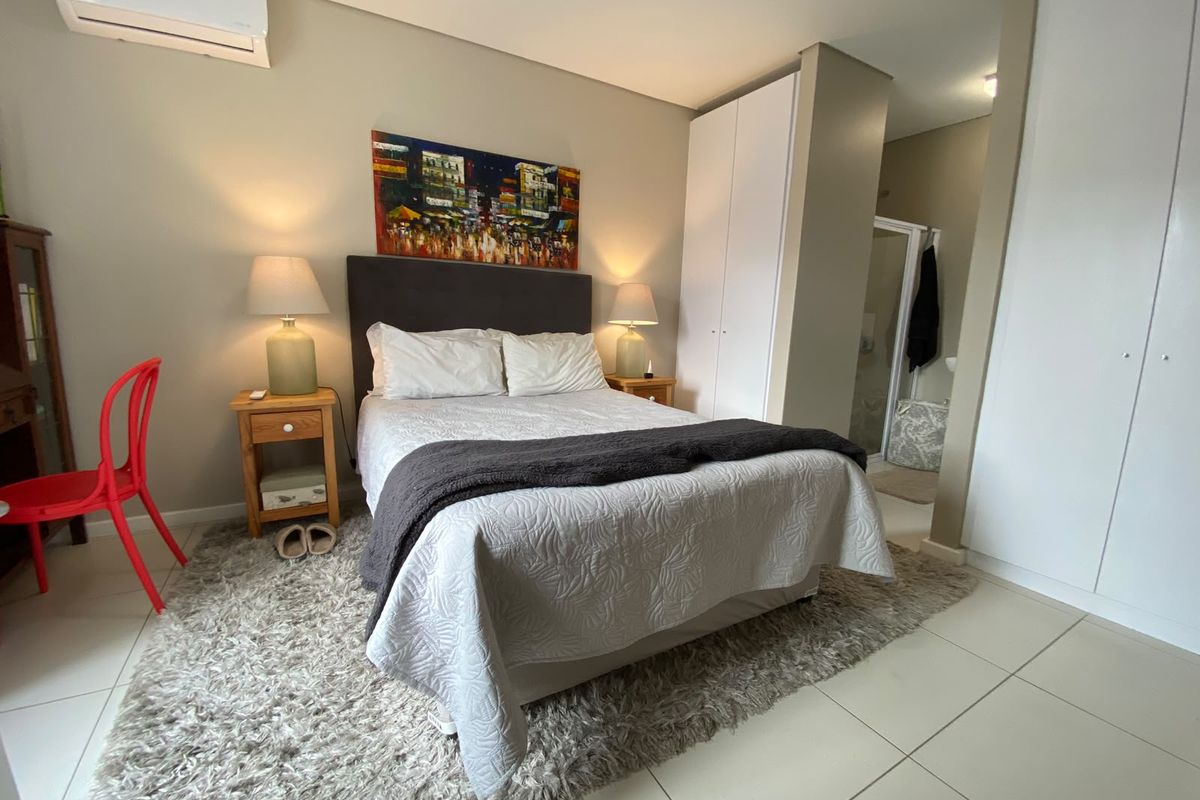 A well-maintained bedroom featuring tiled flooring, built-in cupboards, and an integrated split-system air conditioner, with direct access to an en-suite bathroom.