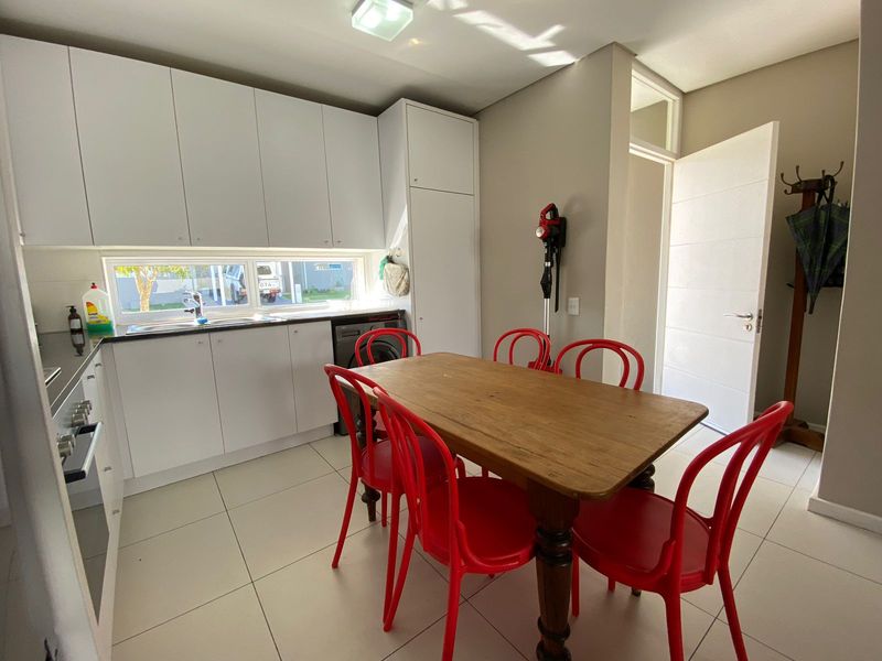 A functional kitchen featuring white cabinetry, tiled flooring, and integrated appliances, providing a clean and practical space for cooking and dining.