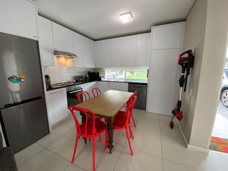 Modern kitchen featuring white cabinetry, dark countertops, integrated appliances, and tiled flooring, offering a clean and functional cooking space.