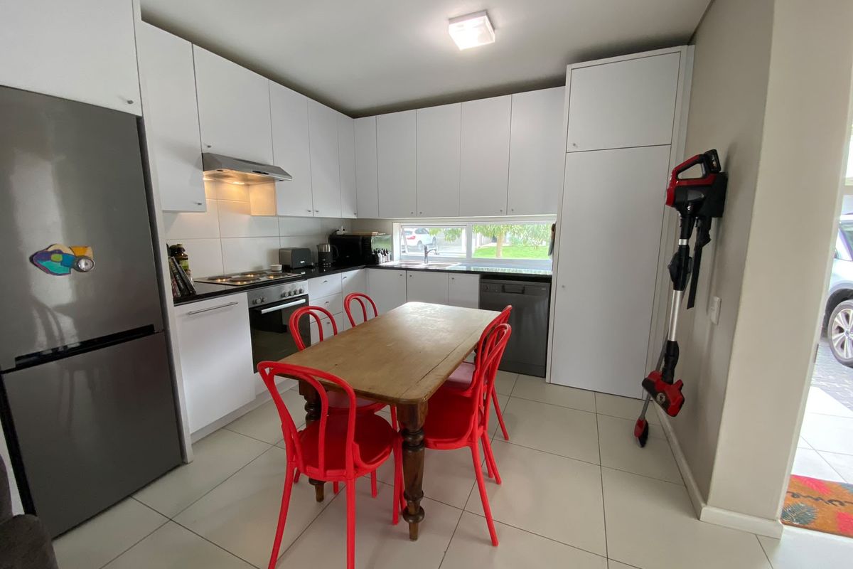 Modern kitchen featuring white cabinetry, dark countertops, integrated appliances, and tiled flooring, offering a clean and functional cooking space.