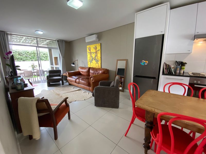 Open-plan living and kitchen area featuring tiled floors, modern cabinetry, built-in appliances, and direct access to an outdoor patio through sliding glass doors.