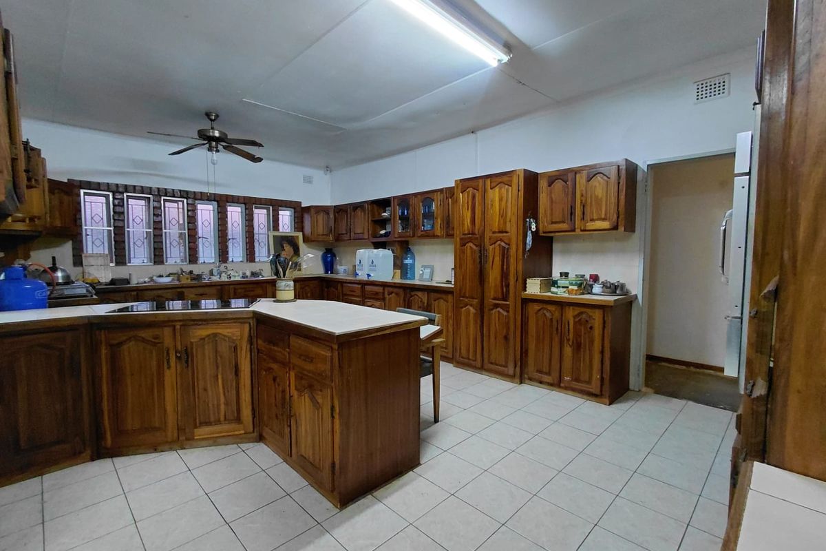 Spacious kitchen featuring extensive wooden cabinetry, a central island, tiled flooring, and functional built-in appliances, offering a traditional layout with ample storage.