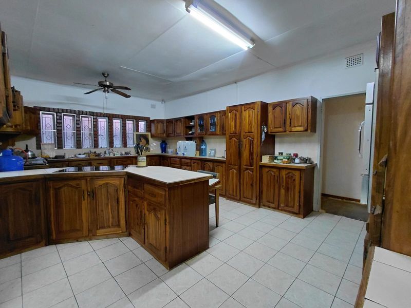 Spacious kitchen featuring extensive wooden cabinetry, a central island, tiled flooring, and functional built-in appliances, offering a traditional layout with ample storage.