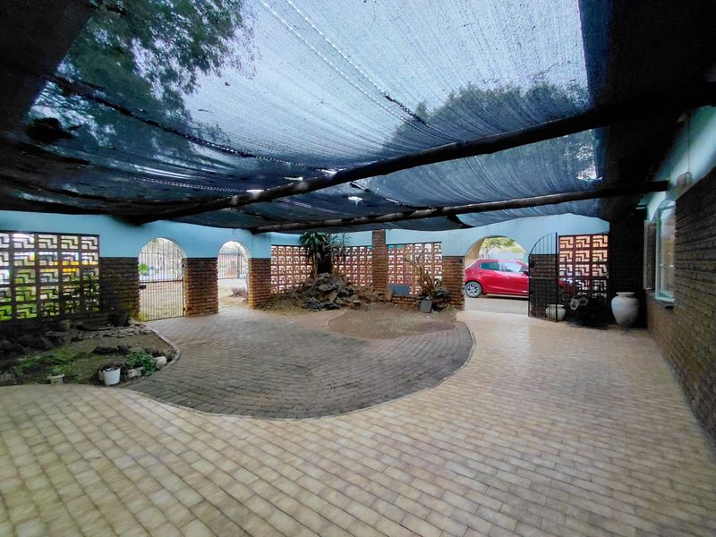 A large covered outdoor patio area featuring decorative breeze block walls, brick paving, and a shade cloth canopy, offering a versatile space for outdoor living.
