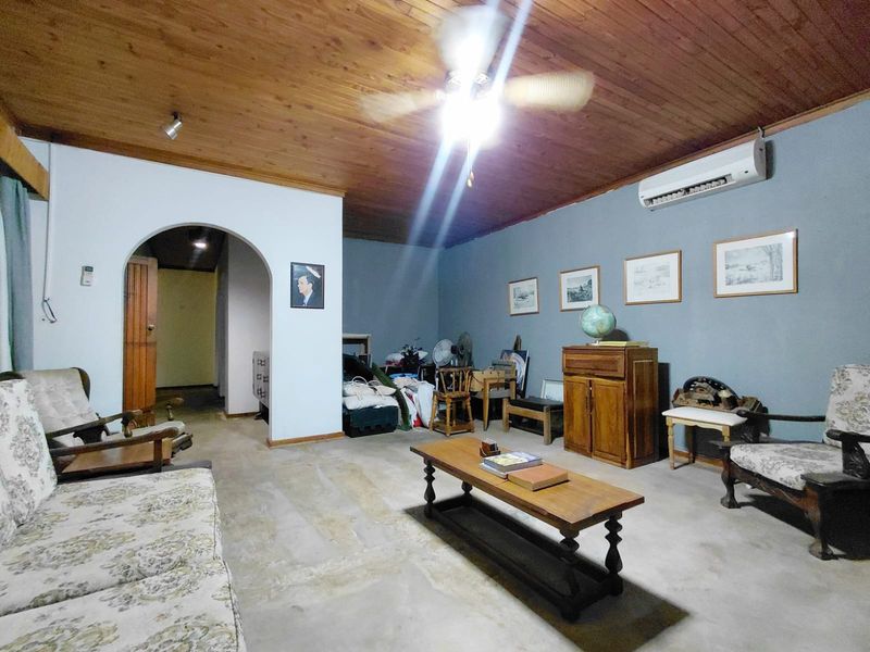 Living room featuring a timber ceiling, split-system air conditioning, and an arched entryway leading to the hallway.