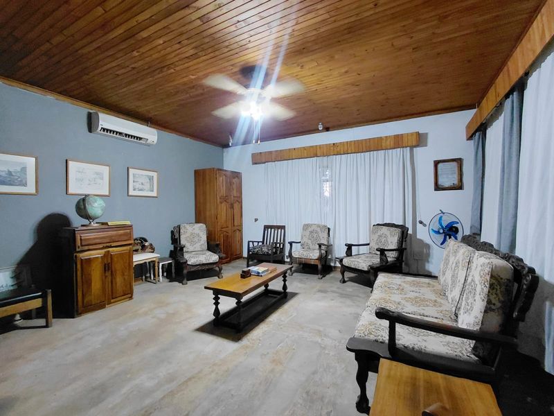 A living room featuring a timber tongue and groove ceiling, concrete flooring, and a wall-mounted split-system air conditioner.