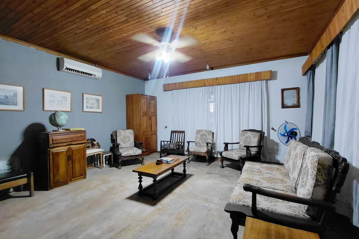 A living room featuring a timber tongue and groove ceiling, concrete flooring, and a wall-mounted split-system air conditioner.