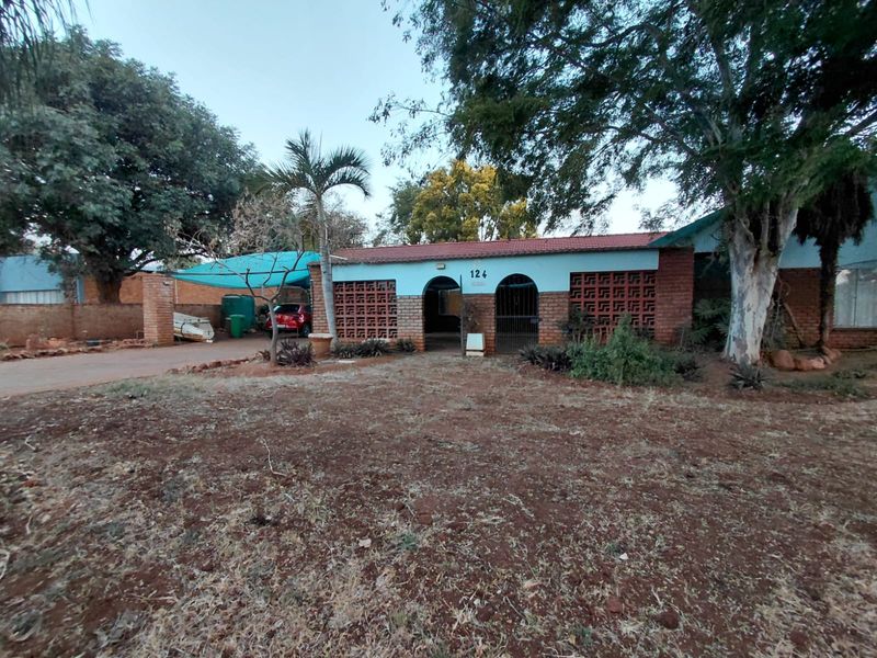 Front elevation of a single-story house featuring a brick facade, decorative breeze block screens, and an attached carport area.