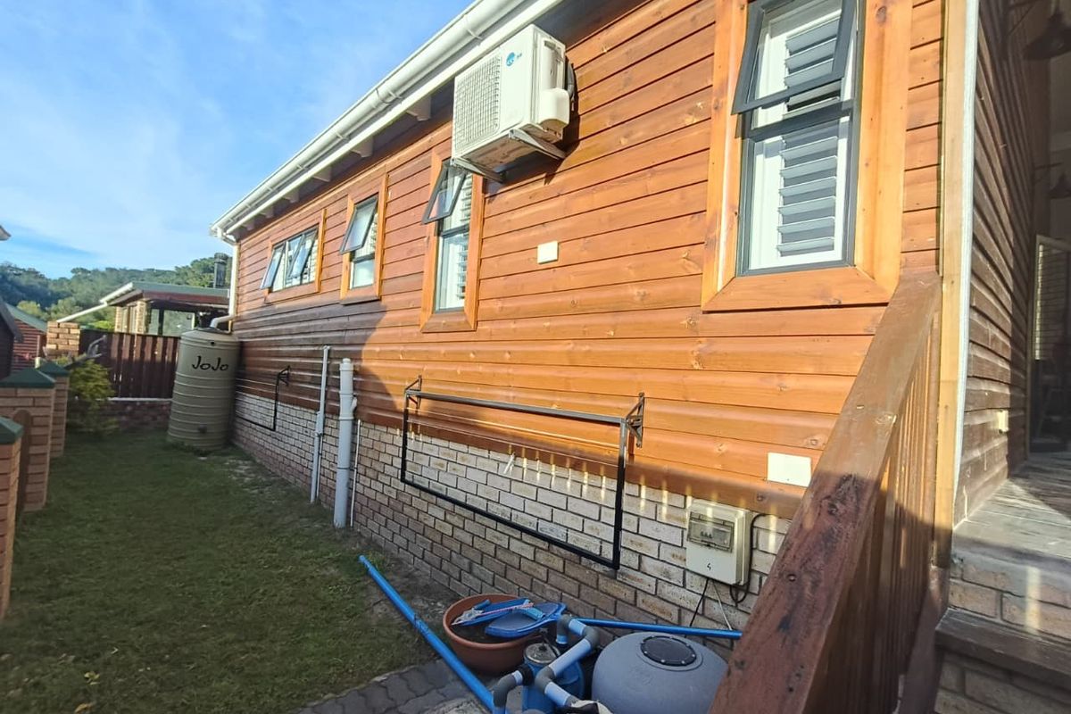 Rear exterior view of the property featuring timber cladding, brick foundation, pool filtration equipment, and a water storage tank.