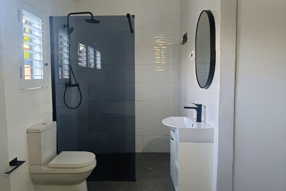 Modern bathroom featuring a walk-in shower with black fixtures, a vanity with basin, and contemporary tiled finishes.