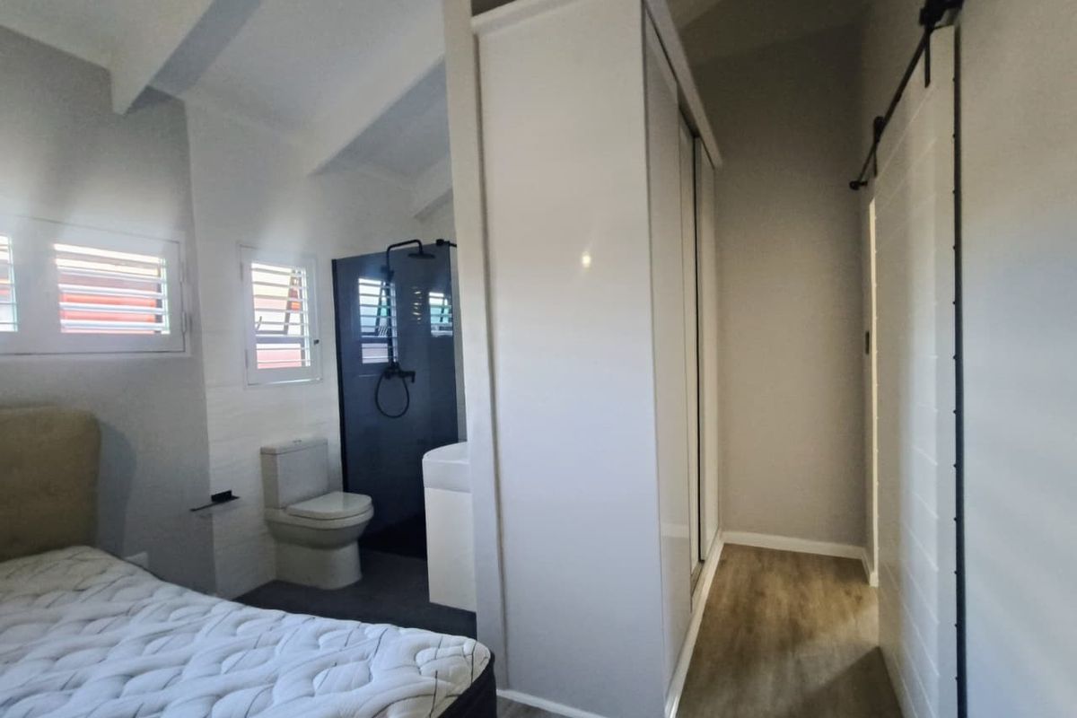 Modern bedroom featuring a built-in wardrobe, sliding barn door, and an integrated en-suite bathroom with a walk-in shower.