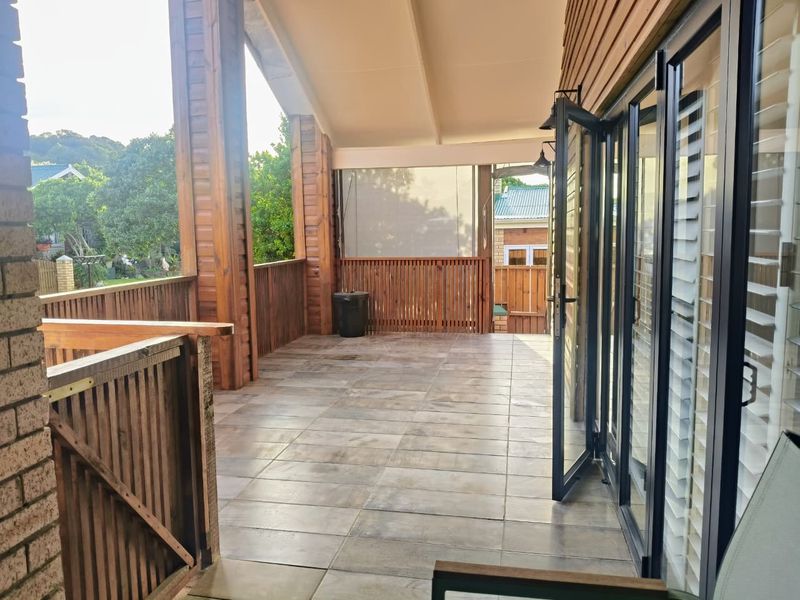 A spacious covered patio featuring tiled flooring, timber balustrades, and large bi-fold doors providing seamless indoor-outdoor flow.