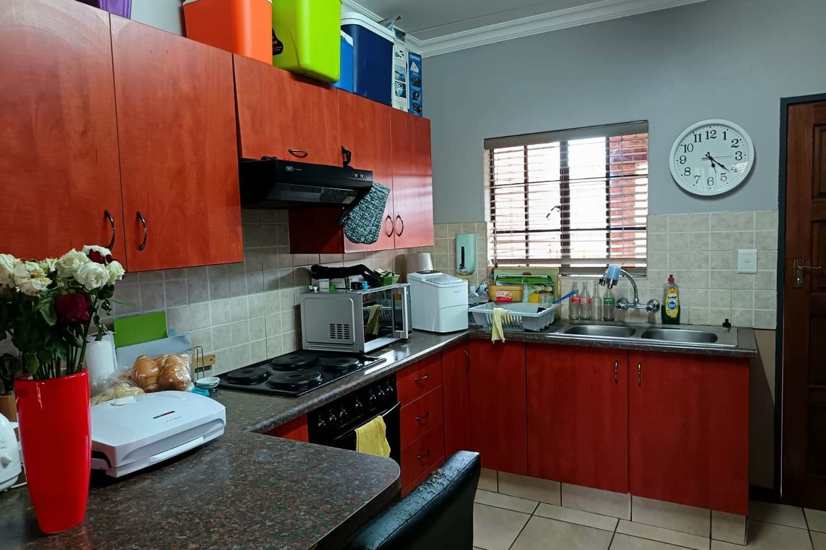 A functional kitchen featuring wood-finish cabinetry, laminate countertops, a double basin sink, and integrated cooking appliances with tiled backsplash and flooring.