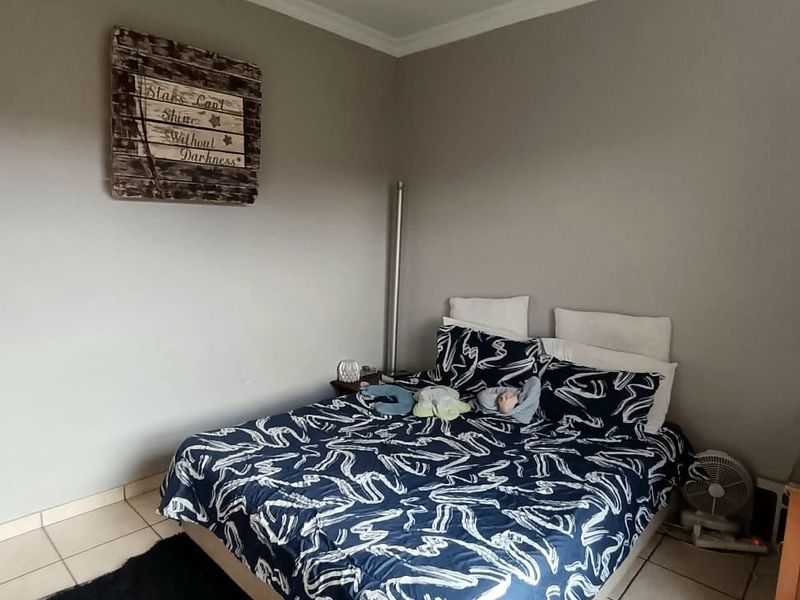 A bedroom featuring neutral wall tones, tiled flooring, and a ceiling fan, providing a functional space ready for personalization.